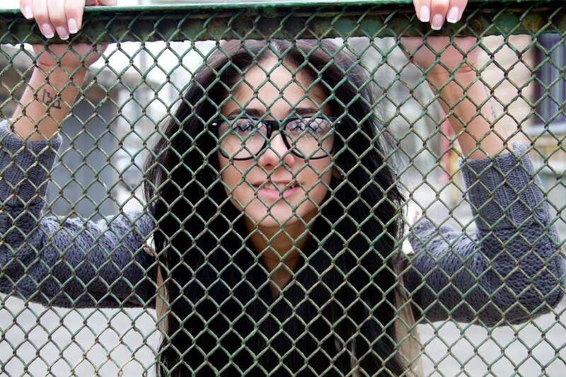 woman behind chain-link fence