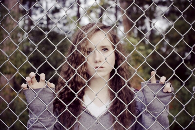 woman behind chain-link fence