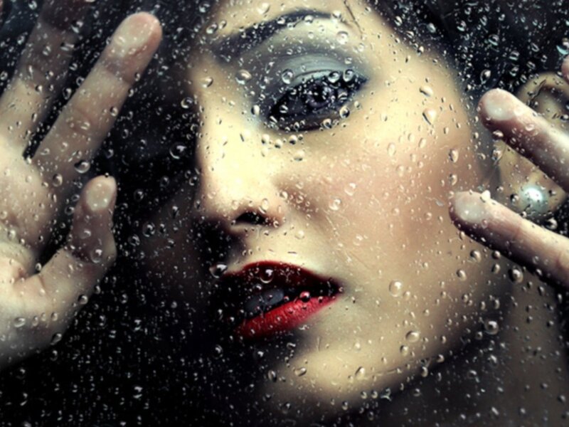 woman behind rain-covered glass