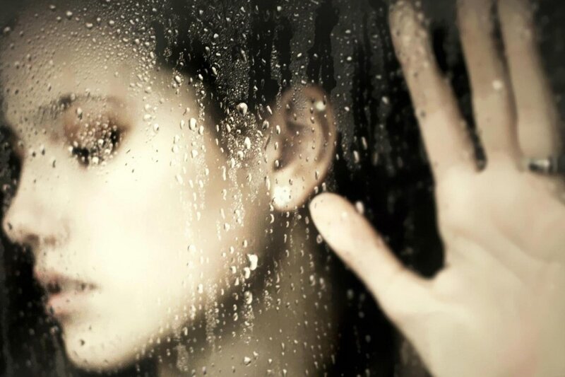 woman behind rain-covered glass