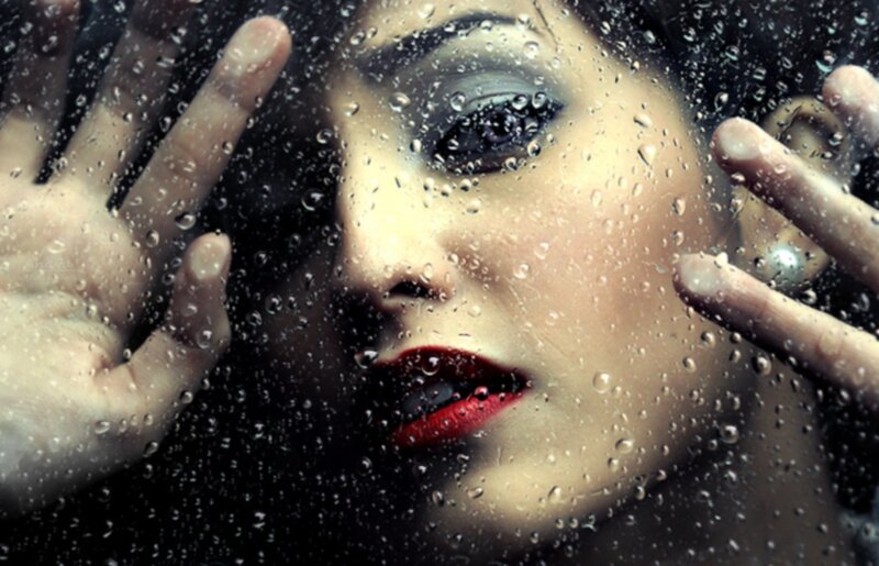 woman behind rain-covered glass