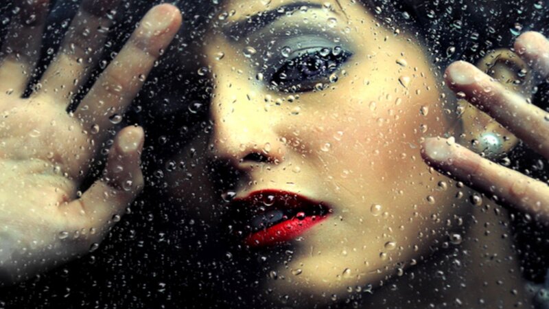 woman behind rain-covered glass