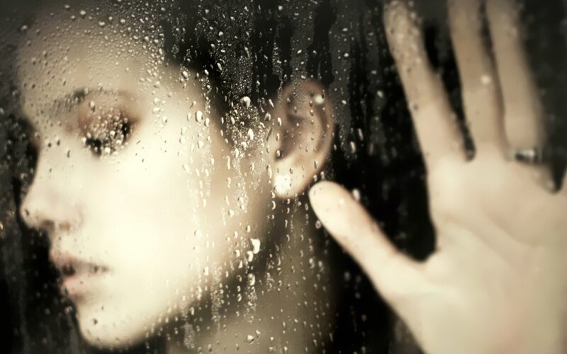 woman behind rain-streaked glass
