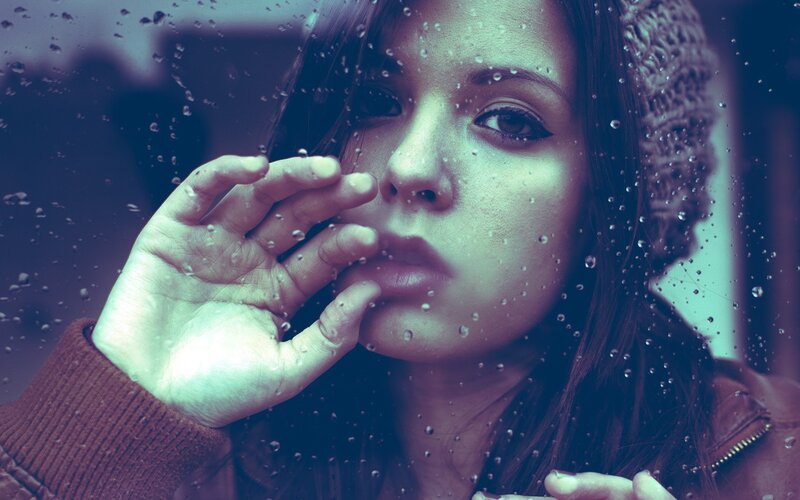 woman behind rain-streaked window