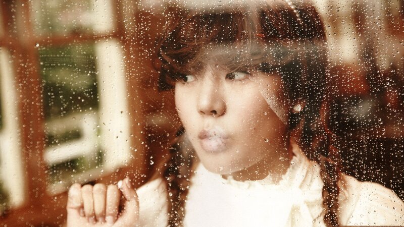 woman behind rain-streaked window