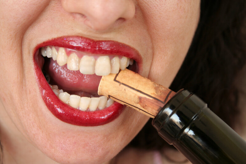 woman biting wine cork