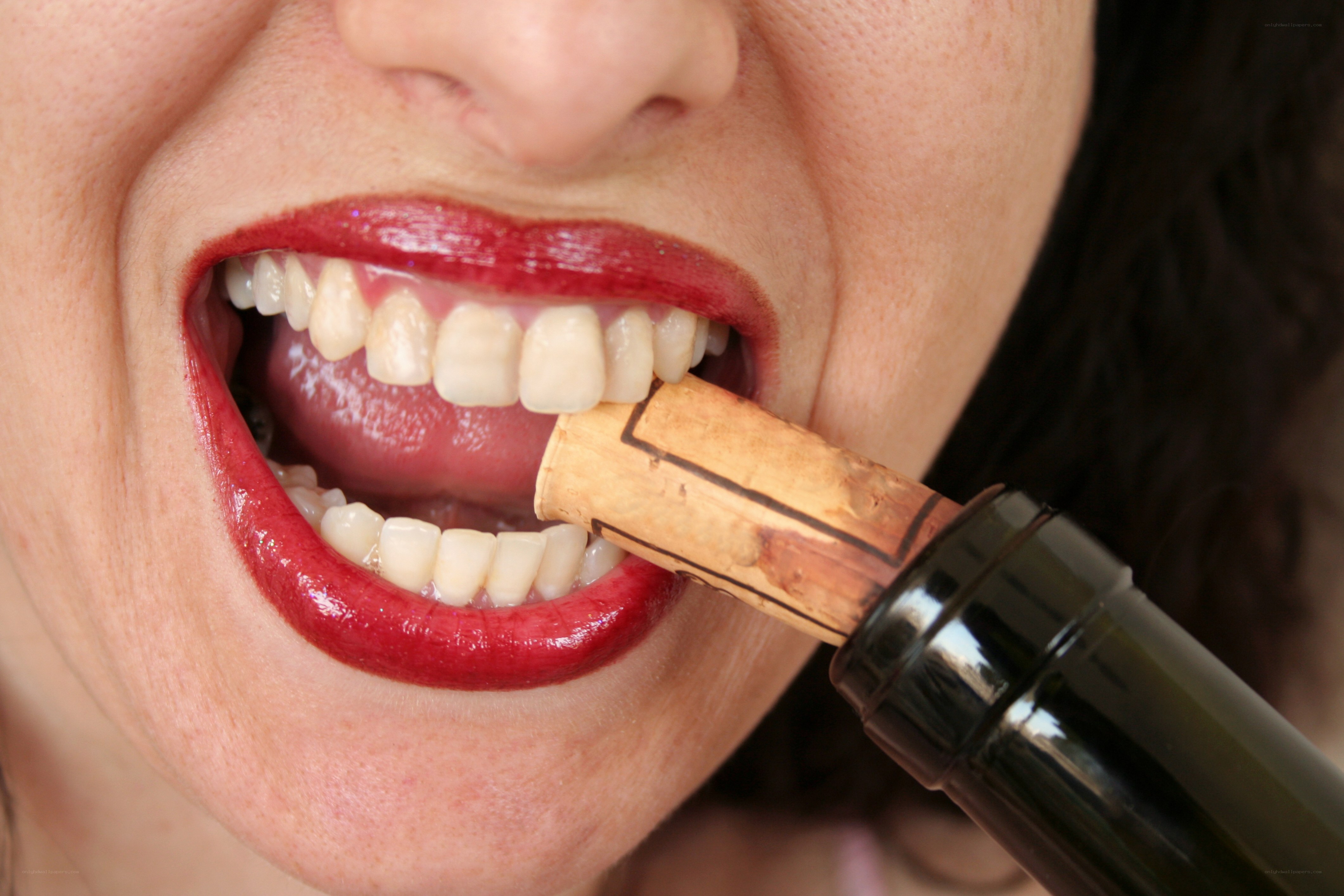 woman biting wine cork