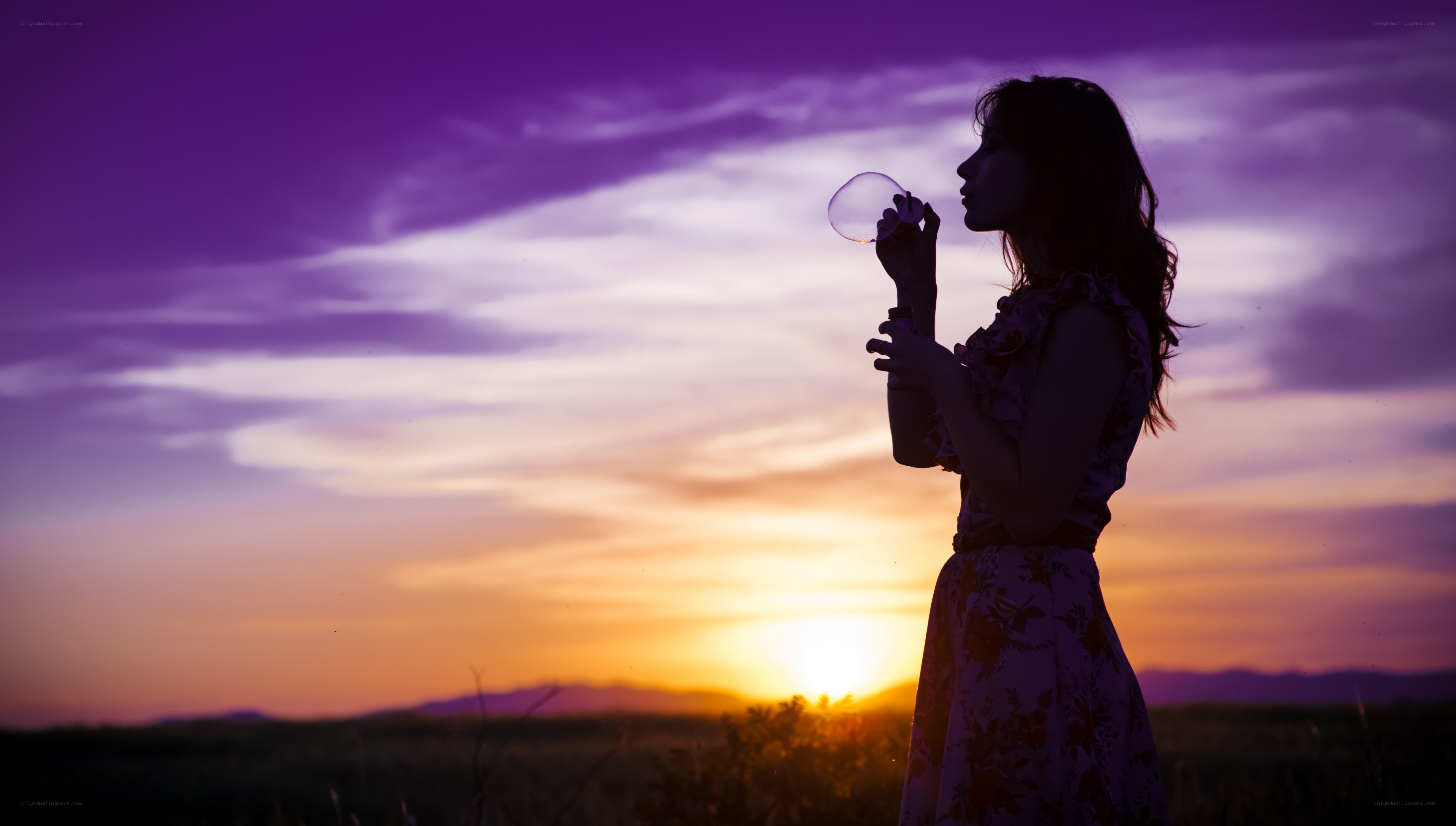woman blowing bubbles at sunset
