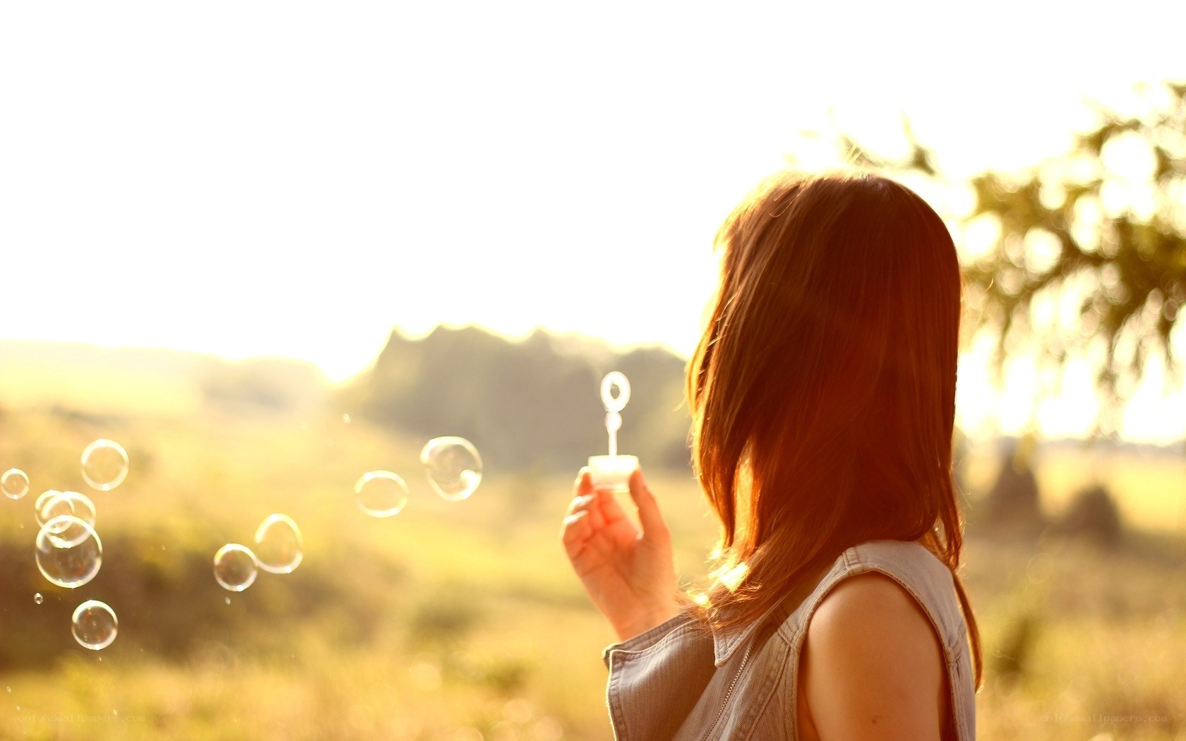 woman blowing bubbles at sunset