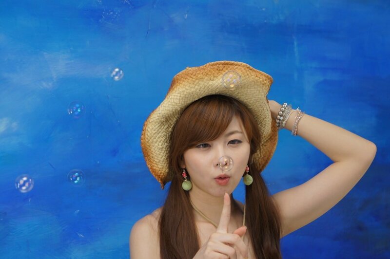 Woman Blowing Bubbles — Blue, Playful, Photograph, Straw Hat, Earrings, Bracelets