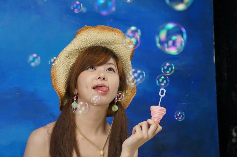 Woman Blowing Bubbles — Blue, Playful, Photograph, Straw Hat, Necklace