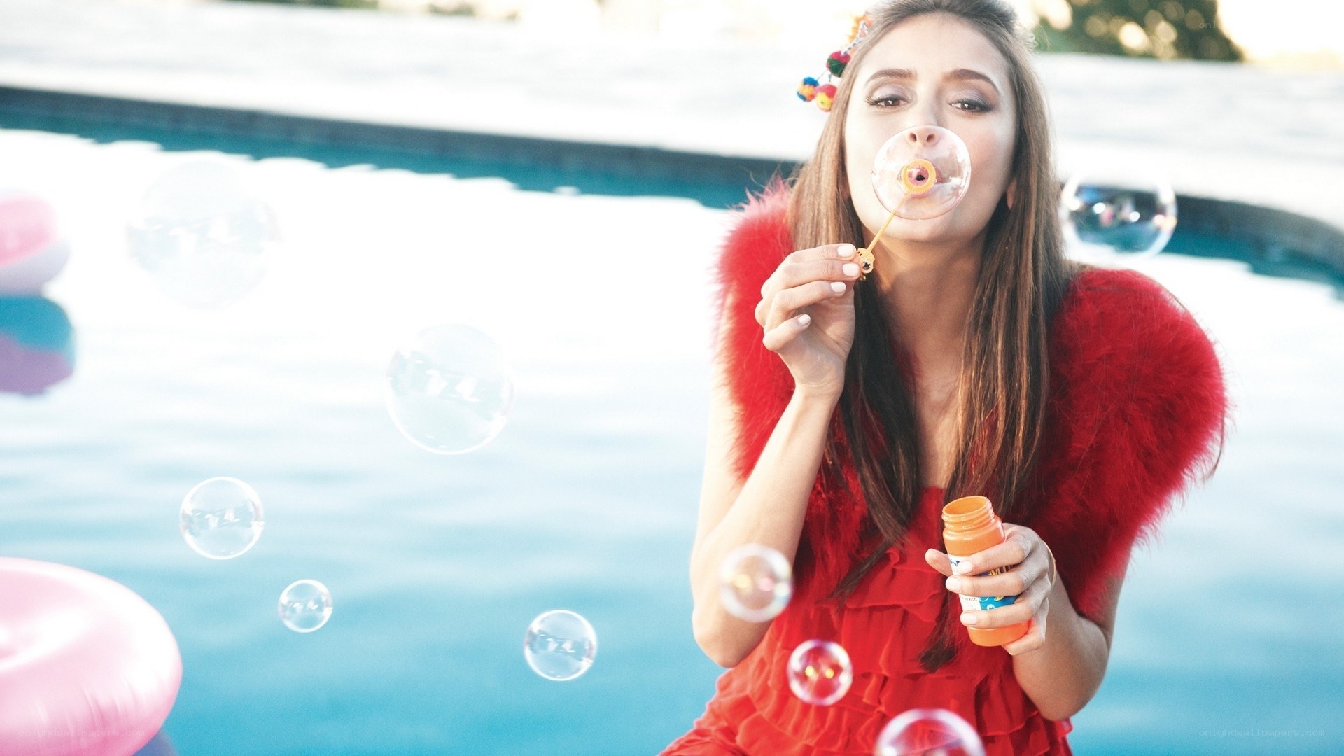 woman blowing bubbles by pool