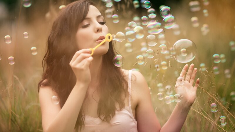 woman blowing bubbles in field