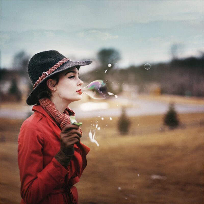 woman blowing bubbles in field