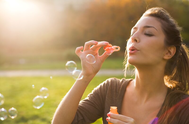 woman blowing bubbles in park