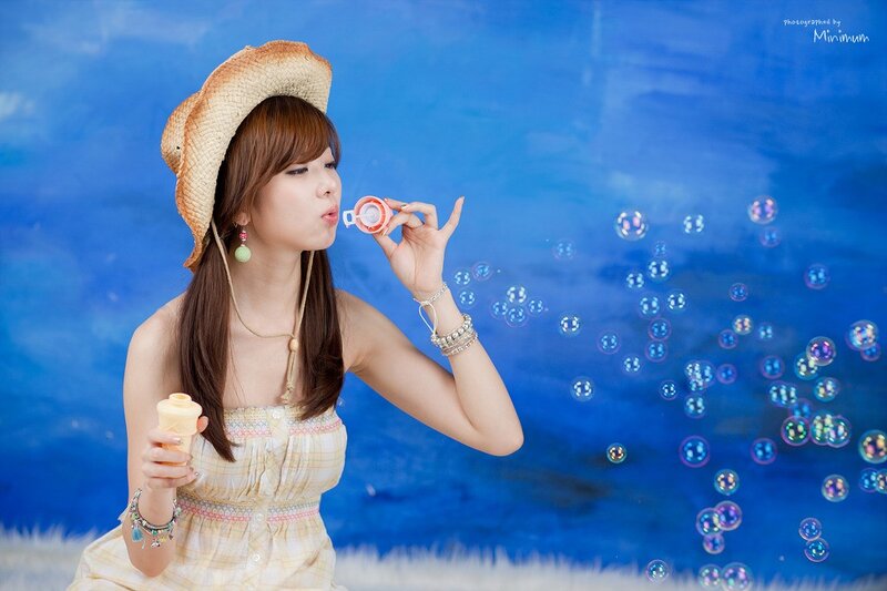 woman blowing bubbles in straw hat