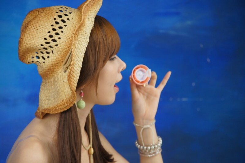 woman blowing bubbles with straw hat