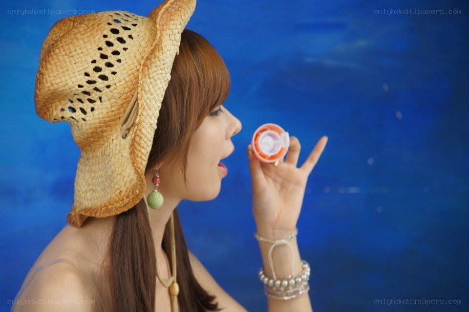 woman blowing bubbles with straw hat