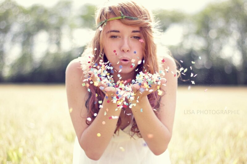 woman blowing confetti in field
