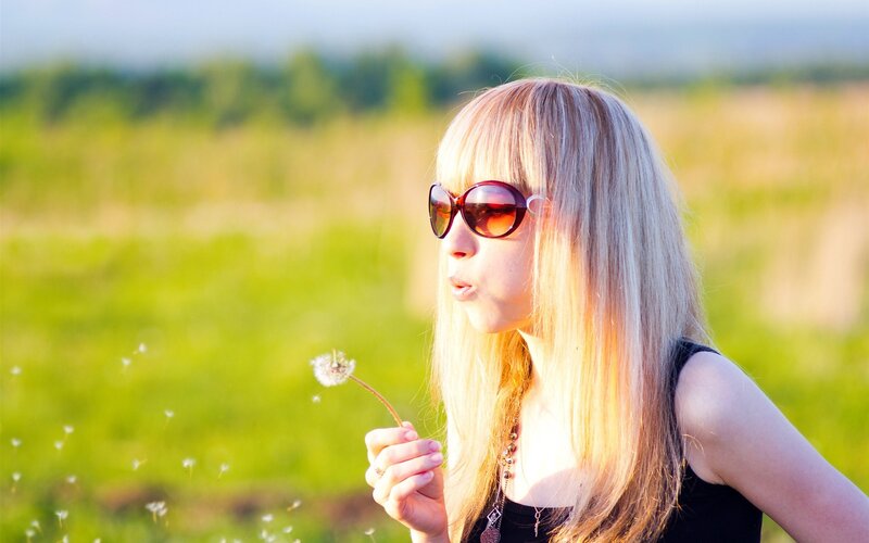 woman blowing dandelion seeds