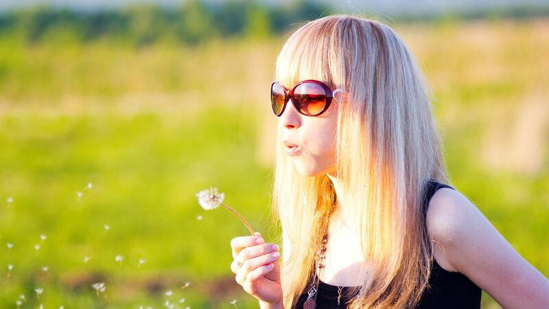 woman blowing dandelion seeds