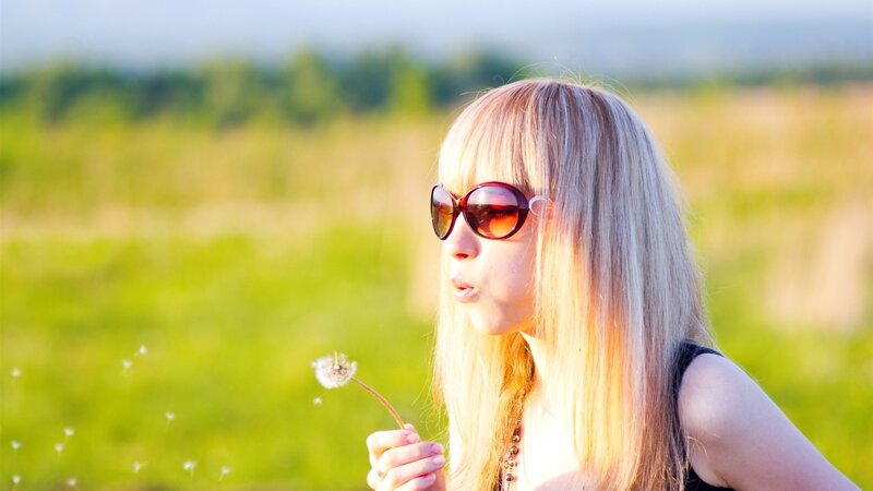 woman blowing dandelion seeds