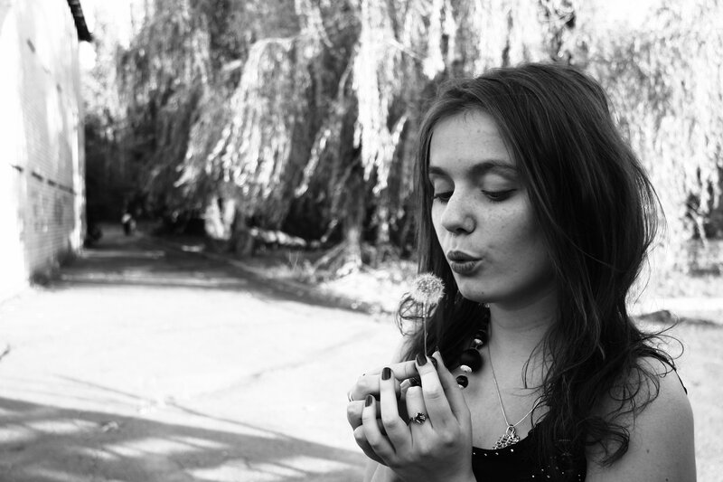 woman blowing dandelion seeds