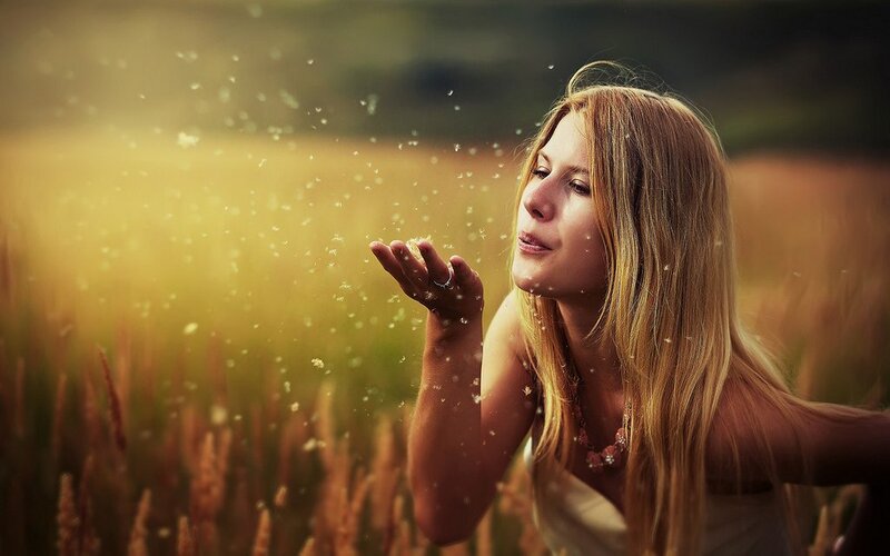 woman blowing dandelion seeds