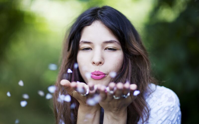 woman blowing flower petals