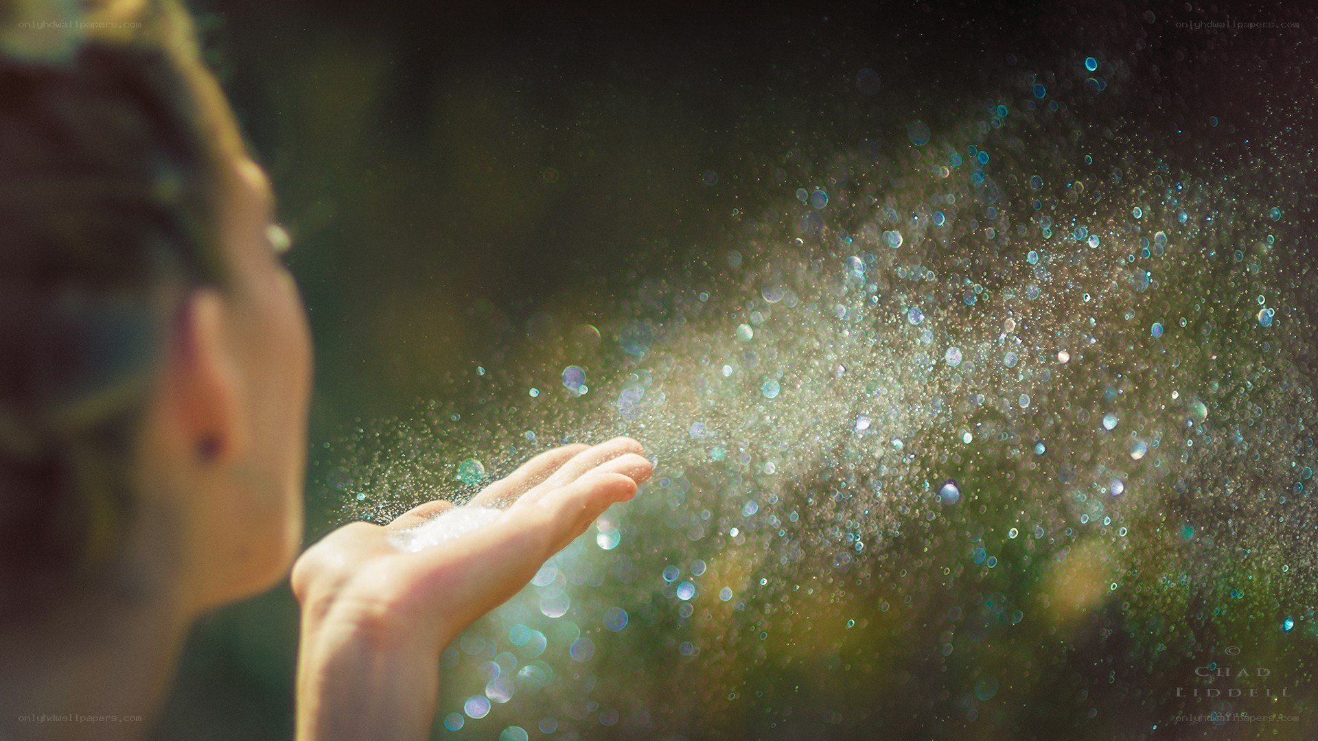 woman blowing glitter particles
