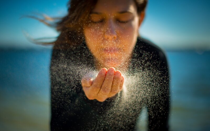 woman blowing sand at beach
