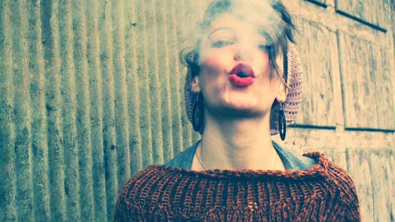 woman blowing smoke in front of wall