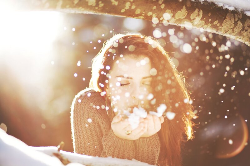 woman blowing snow in sunlight