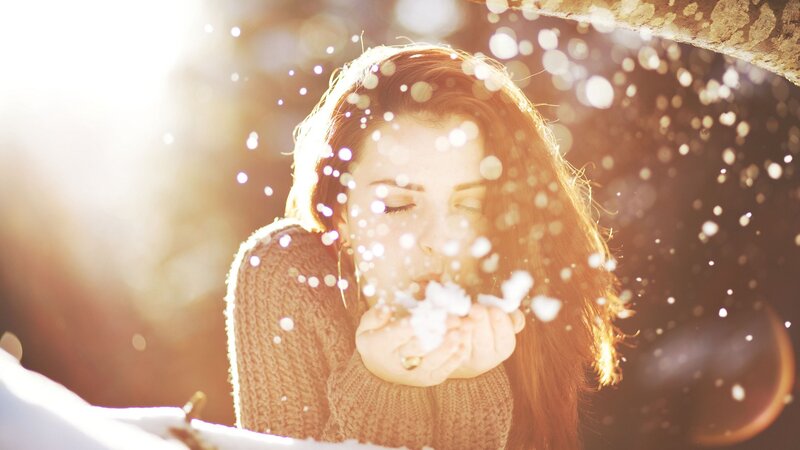 woman blowing snow in sunlight