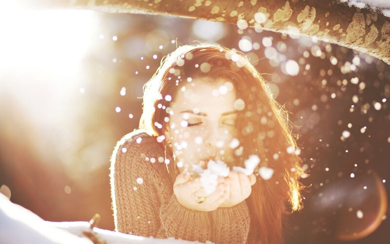woman blowing snow in sunlight