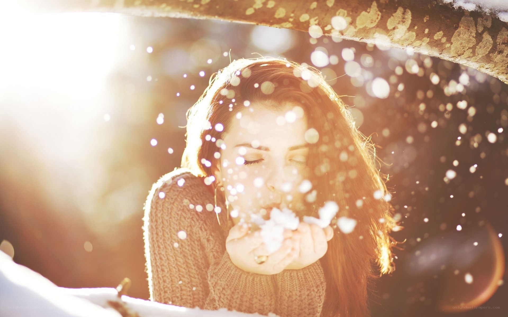 woman blowing snow in sunlight
