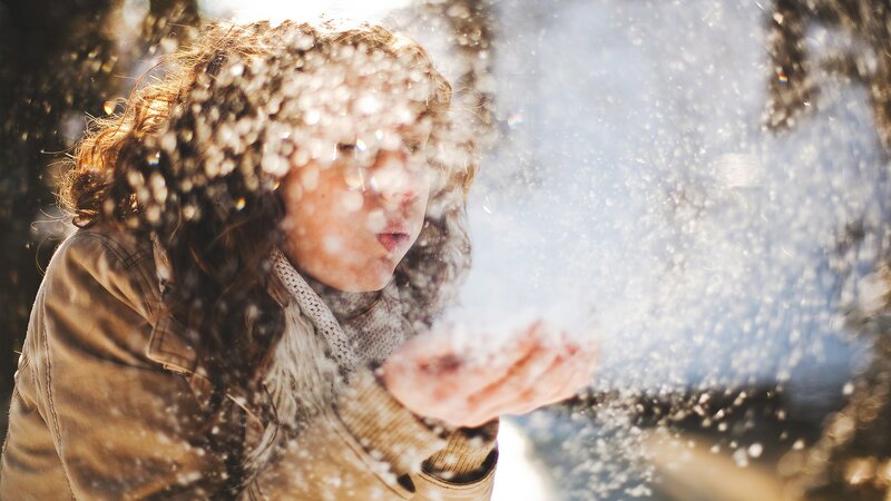 woman blowing snow in winter