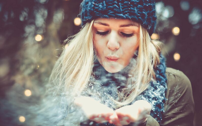 woman blowing snow in winter