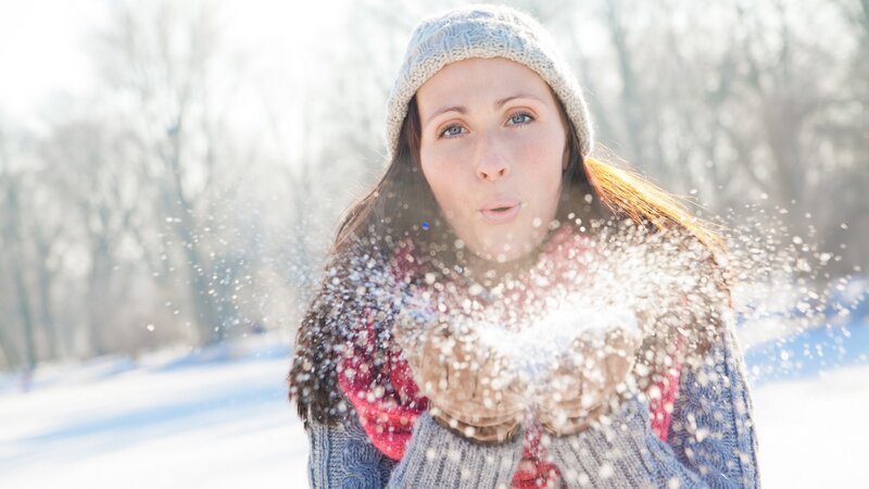 woman blowing snow in winter