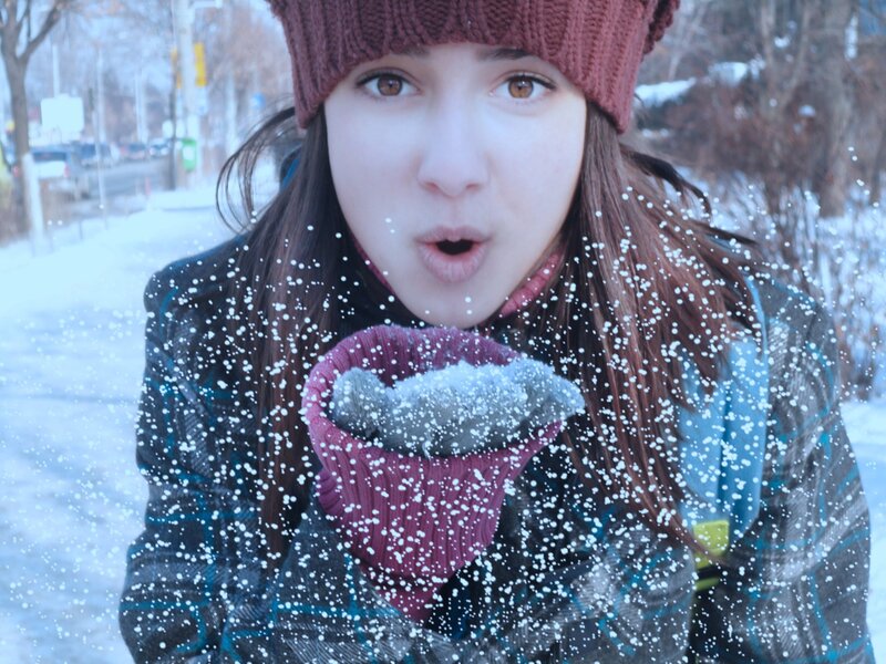 woman blowing snow in winter