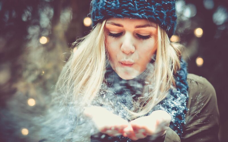 woman blowing snow in winter