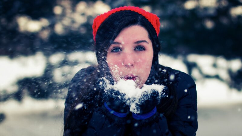 woman blowing snow in winter