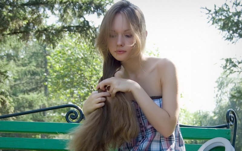 woman braiding hair on bench