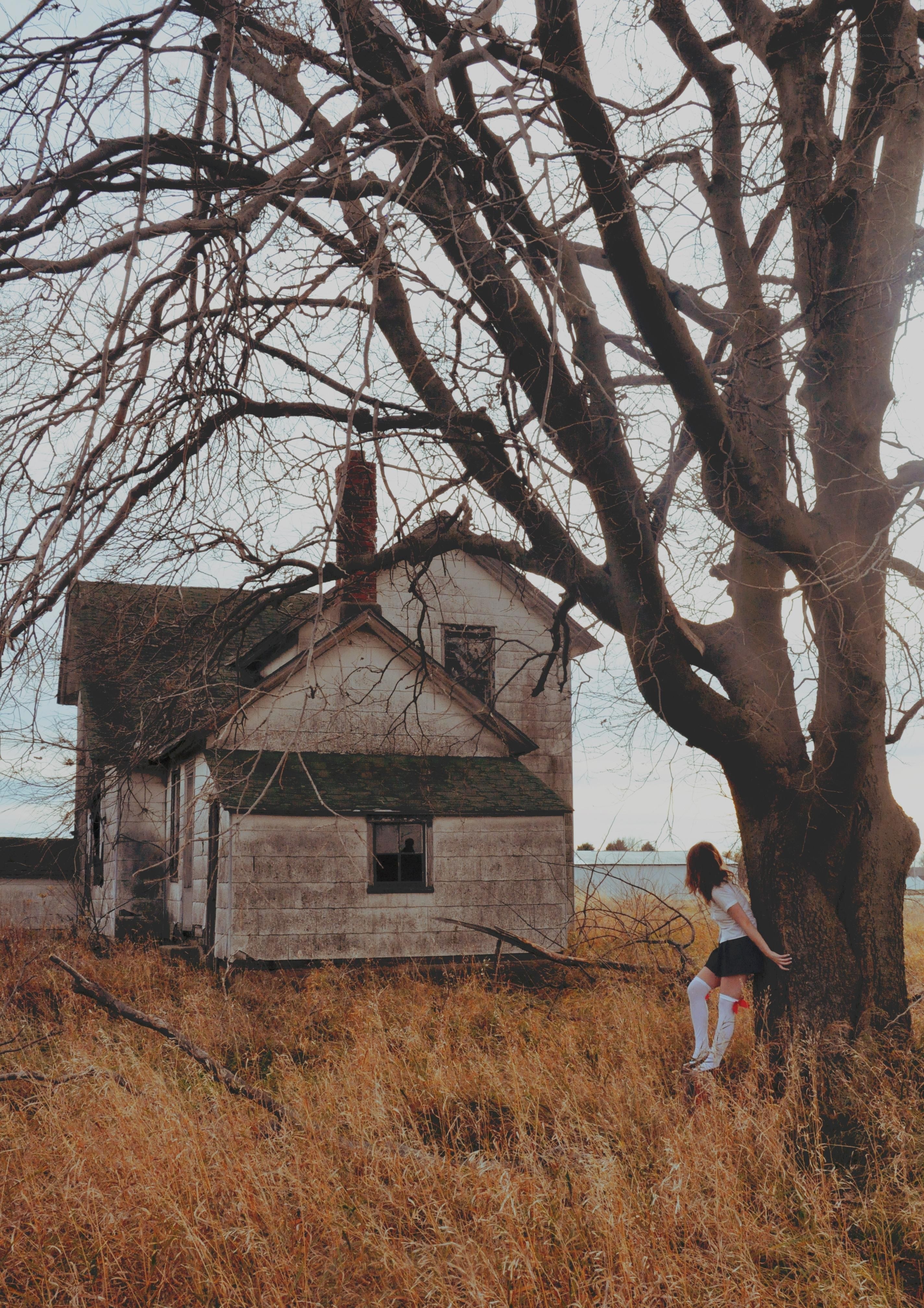 woman by old house and tree