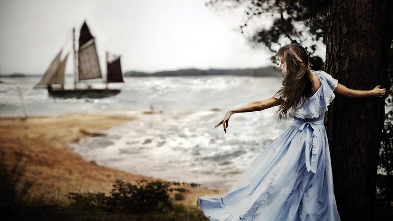Woman by the sea with sailboat