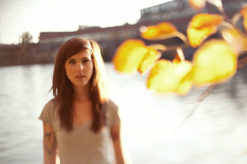 woman by the water with autumn leaves