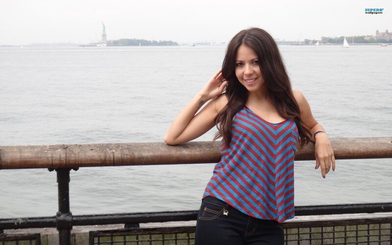 woman by the water with statue of liberty