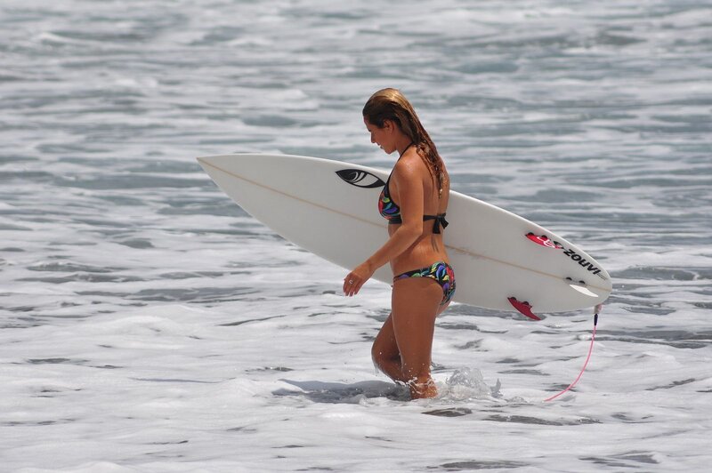 woman carrying surfboard in ocean