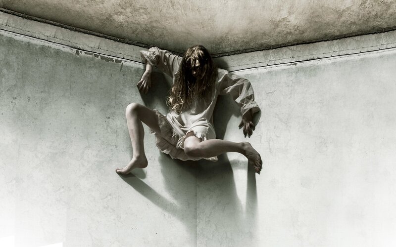 woman clinging to wall in corner