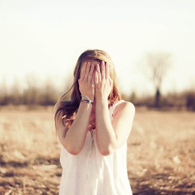 woman covering face in field